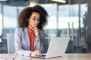 Bir kadın masadaki dizüstü bilgisayarda çalışıyor, kişisel bilgisayarını çıkış aygıtı olarak kullanıyor..