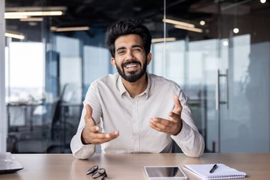 Neşeli Hintli işadamı modern bir ofiste çalışıyor, kendine güvenini ve yaklaşımını sergiliyor ve şık giyiniyor..