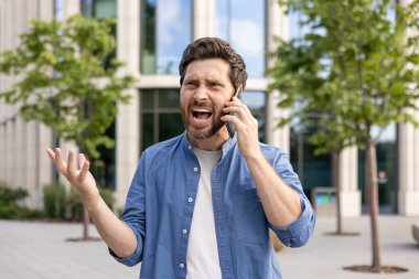 Öfkeli ve hayal kırıklığına uğramış genç adam cep telefonuyla konuşuyor. Şehir merkezinin yakınındaki caddede, bağırıyor ve elleriyle işaret ediyor..