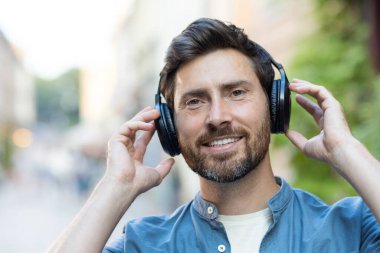 Mutlu, sakallı, olgun bir adam gün batımında şehirde yürüyor, kulaklıklarıyla en sevdiği melodileri dinliyor..