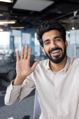 İnternetteki bir toplantıda genç bir Hintlinin el kamerasıyla konuşurken ve selamlaşırken çekilmiş dikey yakın plan fotoğrafı..