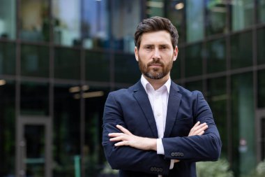 Modern bir ofisin dışında odaklanmış bir ifadeyle takım elbiseli kararlı bir profesyonel adamın portresi..