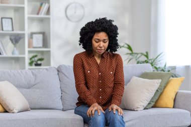 Korkmuş ve üzgün genç bir kadın evdeki kanepede oturmuş depresyon ve panik ataktan muzdarip..