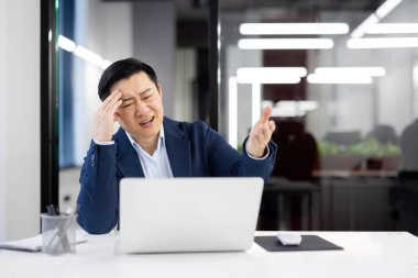 Hüsrana uğramış Çinli şirket patronu iş yerinde acı içinde gözlerini kısarak alnına dokunuyor. Stresli erkek çalışanlardan migren nöbeti için ilaç getirmelerini istedi..