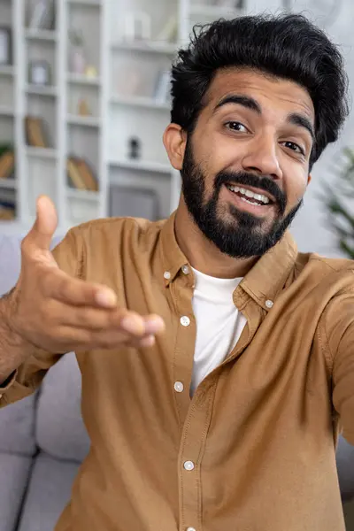 First person view of arab bearded man gesturing with hand while looking at camera during phone video call. Young casually styled male talking with friend while using wireless internet connection.