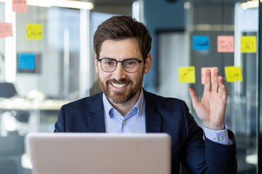 Ofis ortamında dizüstü bilgisayarı üzerinde çalışan takım elbiseli bir profesyonel..