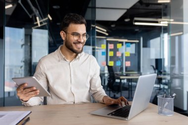 İyi organize edilmiş bir ofis masasında tablet ve dizüstü bilgisayarla, verimliliği ve teknolojiyi somutlaştıran profesyonel çoklu görev..