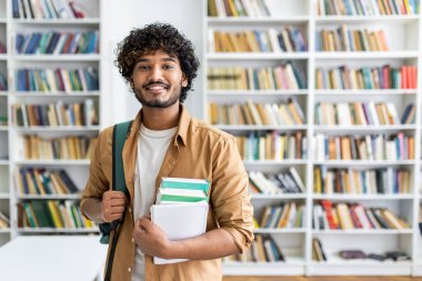 Kitapçıda kameraya gülümserken sırt çantası takan ve elinde bir yığın kitap tutan mutlu, tıraşsız adam. İyimser sınıf öğrencisi üniversitedeki yeni akademik dönemin başlangıcı için alım yapıyor..