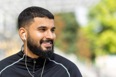 Bir adam dışarıda biraz dinlenmek için antrenmanını durdurur, sağlık ve zindelik dolu bir yaşam tarzı gösterir..