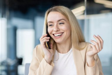 Neşeli bir kadın profesyonel telefon görüşmesi yapıyor. Ofis ortamında güven ve neşe yayıyor..