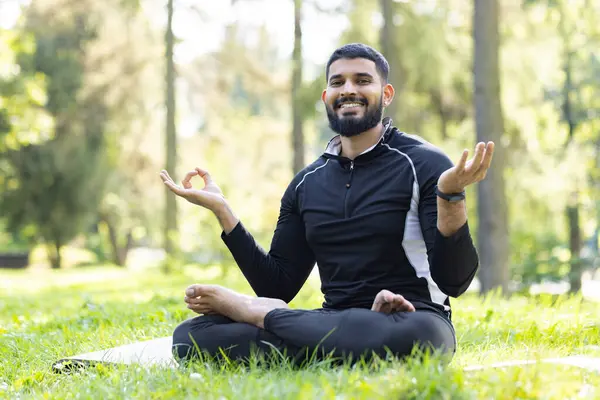 A serene image capturing a man in meditation, surrounded by the tranquility of a lush green park.