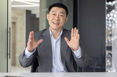 İş ortamındaki profesyonel Asyalı bir adam iş yerinde iletişim kurduğunu gösteren bir video görüşmesine katılmış..