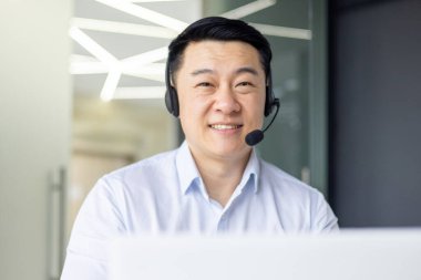 Profesyonel bir Asyalı adam modern bir ofiste kendini işine adamış ve odaklanmıştır..