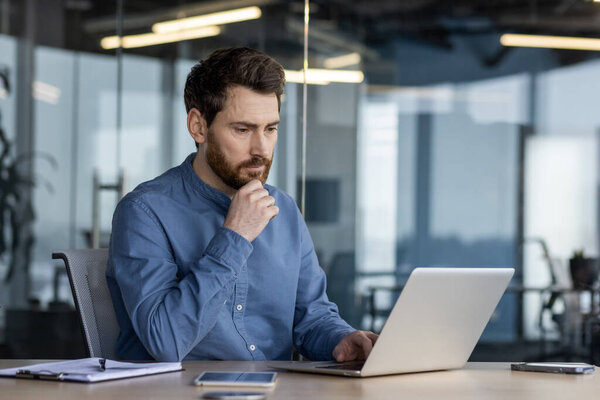 A focused professional engaging with a laptop in a well-lit, contemporary office setting, embodying efficiency and technology.