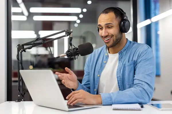 stock image Focused Indian man records a podcast from his stylish living room, representing modern home-working scenarios.