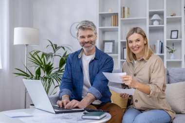 Olgun bir çift koltuklarında rahatça oturur mali durumlarını birlikte idare ederken gülümserler. Huzurlu bir ofis arkaplanı olan, rahat bir ortam..