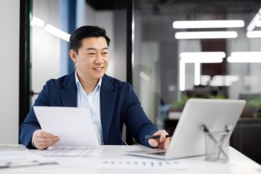 Modern ofis iç mimarisinin arka planında masa başı çalışan resmi kıyafetli mutlu bir insan. Günlük görevlerin listesini hazırlayan ve proje raporuyla e- posta gönderen meşgul yönetici.