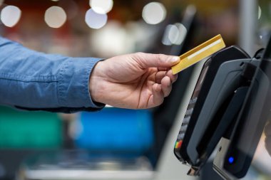 Yetişkin insan eliyle süper marketin postal terminaline altın kredi kartı yerleştiriyor. Kimliği belirsiz kişi, para kullanmadan hiç bir işlem ve satın alma için ödeme yapıyor..