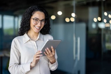 Genç ve başarılı kadın programcı, tablet bilgisayarlı kadın mühendisin portresi ofis içinde çalışıyor kameraya bakarak gülümseyen uygulamaları test etmek için tablet kullanıyor. .