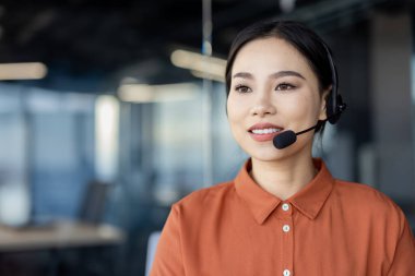 Modern bir ofis alanında çalışırken kulaklık takan kendine güvenen iş kadını profesyonellik ve yakınlık gösteriyor..