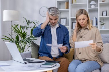 Finansal belgeleri incelerken koltukta oturan endişeli çift maddi sıkıntı ve zorluklar yaşıyor.