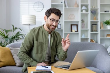 Gülümseyen bir adam dizüstü bilgisayarından online video dersi veriyor, meşgul ve hevesli görünüyor..