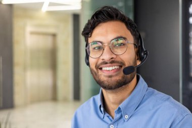 Gülümseyen müşteri hizmetleri temsilcisi, modern ofis ortamında müşterilere yardımcı olmak için kulaklık takıyor. İş, iletişim ve destek kavramları için mükemmel.