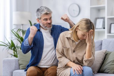 Orta yaşlı bir çift oturma odasında hararetli bir tartışma yaşıyor. Kadın üzgün ve üzgün görünürken adam gözle görülür bir şekilde kızgın..