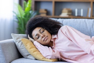 Genç bir kadın rahat bir evde, rahat bir oturma odasında, bir kanepede huzur içinde uyuyor..