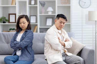 Asyalı çift oturma odasındaki kanepede otururken üzgün ve mesafeli hissediyorlar. Aralarında çatışma ve anlaşmazlık olduğu aşikar..