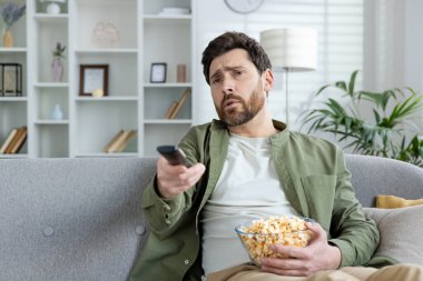 Depresyondan muzdarip genç bir adam evinde kanepede oturup televizyon izliyor elinde bir kase patlamış mısır tutuyor ve uzaktan kumanda kullanıyor..