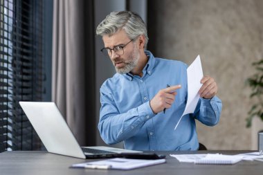 Olgun iş adamı, video görüşmesinde, ev ofisinden uzaktan çalışan belgeleri açıklıyor..