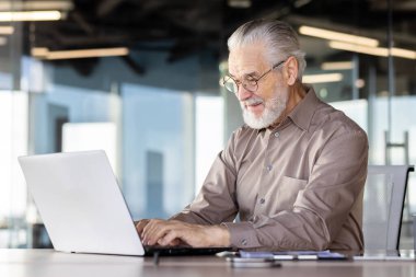 Üst düzey işadamı modern ofis masasında dizüstü bilgisayarla çalışıyor..