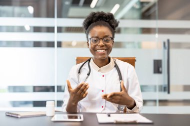 Ofisteki bir video görüşmesi sırasında steteskoplu bir doktor gülümsüyor ve konuşuyor. Sağlık hizmetlerinde teknoloji.