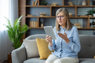 Evde kıdemli bir kadın bir psikologla video görüşmesi yapıyor, endişelerini dile getiriyor ve profesyonel tavsiye istiyor..