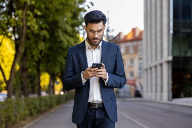 Sonbaharda şehir caddesinde yürürken takım elbise giyen bir işadamı akıllı telefon kullanır. Genç profesyonel mesajları kontrol ediyor ve açık havada bağlı kalıyor. Kentsel yaşam tarzı, modern teknoloji konsepti