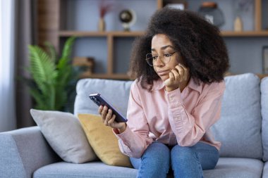 Kanepede oturan, sıkılmış ve telefonuyla ilgilenmeyen genç bir kadın. Evde vakit geçirirken kendini yalnız ve kopuk hissediyor. Can sıkıntısı, yalnızlık ve ilgisizlik kavramı..