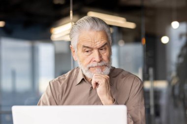 Modern bir ofiste kıdemli bir işadamı. Dizüstü bilgisayarıyla çok meşgul. Görüntü odaklanmayı, düşünmeyi ve profesyonel bir çevreyi betimliyor. Üst düzey profesyonellerle ilgili konular için ideal