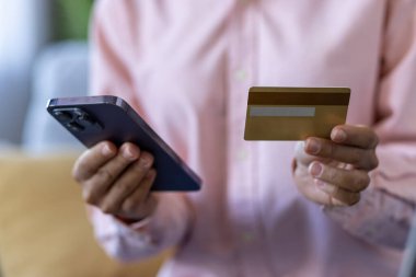 Çevrimiçi alışveriş ya da cep telefonu ödemesini gösteren akıllı telefon ve kredi kartı olan kişilere yakın çekim. Teknoloji, finans ve ecommerce kavramları modern yaşam tarzında tasvir edilmiştir.
