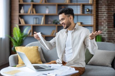 Memnuniyet duyan ve gülümseyen Hintli genç adam belgelere, faturalara ve makbuzlara bakıyor..