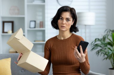 Evdeki hayal kırıklığına uğramış ve üzgün genç bir kadının portresi. Kanepede oturuyor, elinde bir telefon ve açık bir paket var. Yanlışlıkla teslim edilmiş ve zarar görmüş..