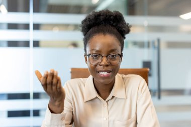 Modern ofiste gözlüklü profesyonel bir iş adamı. Kendine güvenen, odaklanmış ifade, fikirleri tartışan. Arkaplanda ofis dekorasyonu var. Uzaktan çalışma ve iletişim kavramı