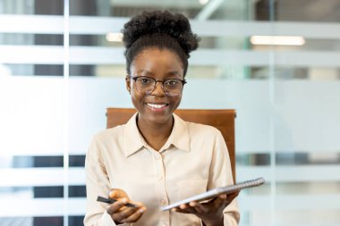 Ofis telefonunda gülümseyen kendine güvenen bir iş kadını. Profesyonel not defteri kalemi, toplantı için hazır. Modern ofis dekorasyonu kurumsal ortamı geliştirir. Uzak iş iletişimi kavramı