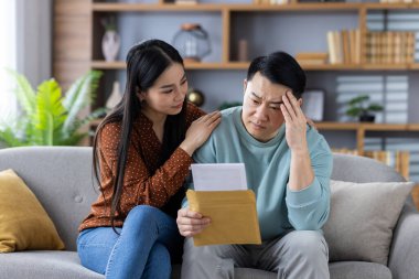 Asyalı çift evde birlikte kötü haberler okuyor, endişe ve stres gösteriyorlar. Elinde belge tutan bir adam, onu rahatlatan bir kadın. Zor zamanlar geçiren çift..