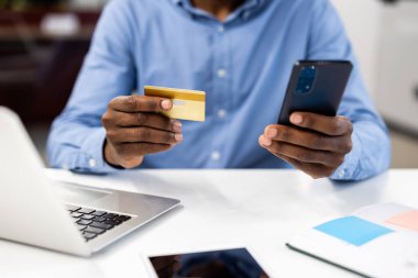 İş ortamında online işlem için kredi kartı ve akıllı telefon tutan bir adam. Teknoloji dijital alışveriş ve mobil bankacılık için kolaylığı artırıyor. E-ticaret ve mali güvenlik kavramını.