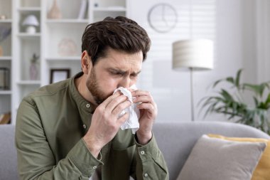 Kanepede peçeteye hapşıran bir adam alerji ya da soğuk algınlığını gösterir. Sıcak atmosferi olan kapalı bir ortam. Sahne sağlık, hastalık, ev yapımı tedaviler ve mevsimsel sorunları betimliyor.