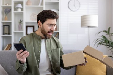 Kanepede oturan sinirli adam elinde akıllı telefon ve boş bir kutu tutuyor. Çevrimiçi alışveriş sırasındaki hayal kırıklığını ve karmaşayı ifade eder. Modern zorluk e-ticaret ve müşteri memnuniyetsizliğini yakalıyor