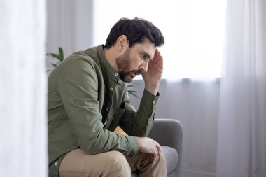 Stresli adam koltukta oturuyor, eli alnında, endişeli görünüyor. Kaygıyı, hayal kırıklığını ve düşüncelere dalmayı ifade eder..