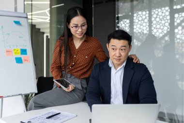 İş yerinde kur yapma, el ele tutuşan erkek omuz omuza, iki Asyalı çalışan iş yerinde birlikte çalışıyor..