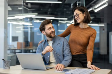 Kadın iş yerindeki adamla flört ediyor, çalışanların dul eşleri bilgisayarla çalışırken mutlu bir şekilde gülümsüyor..